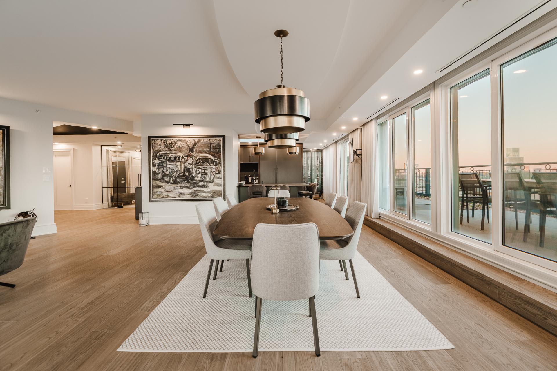 Salle à manger sous un luminaire contemporain, bordée de portes-fenêtres donnant sur la terrasse